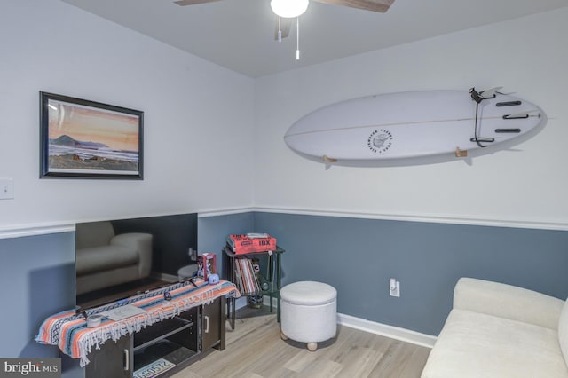 living area with baseboards, ceiling fan, and wood finished floors