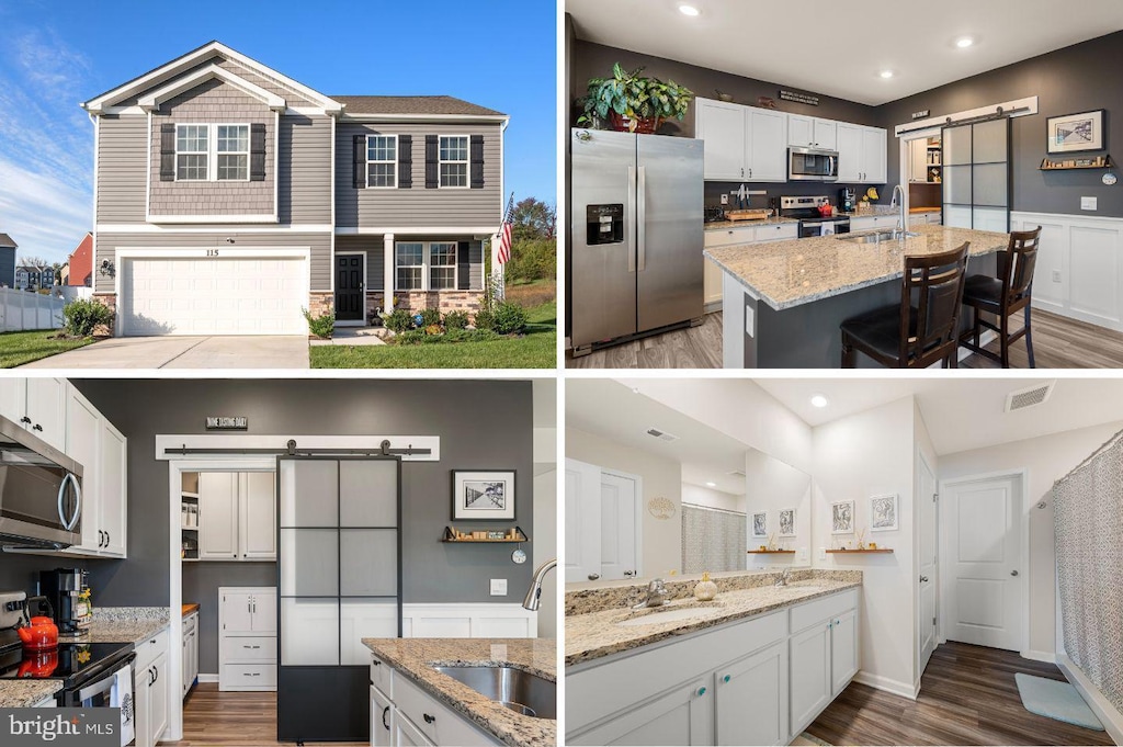 kitchen with wainscoting, stainless steel appliances, a barn door, and a sink