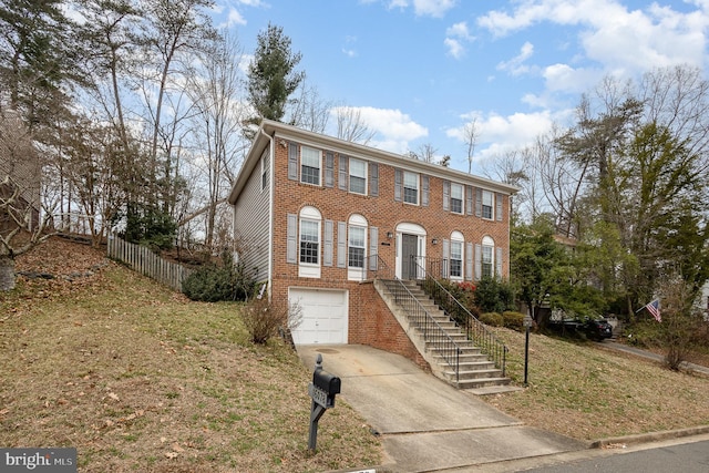 colonial home featuring a garage, brick siding, concrete driveway, and stairway