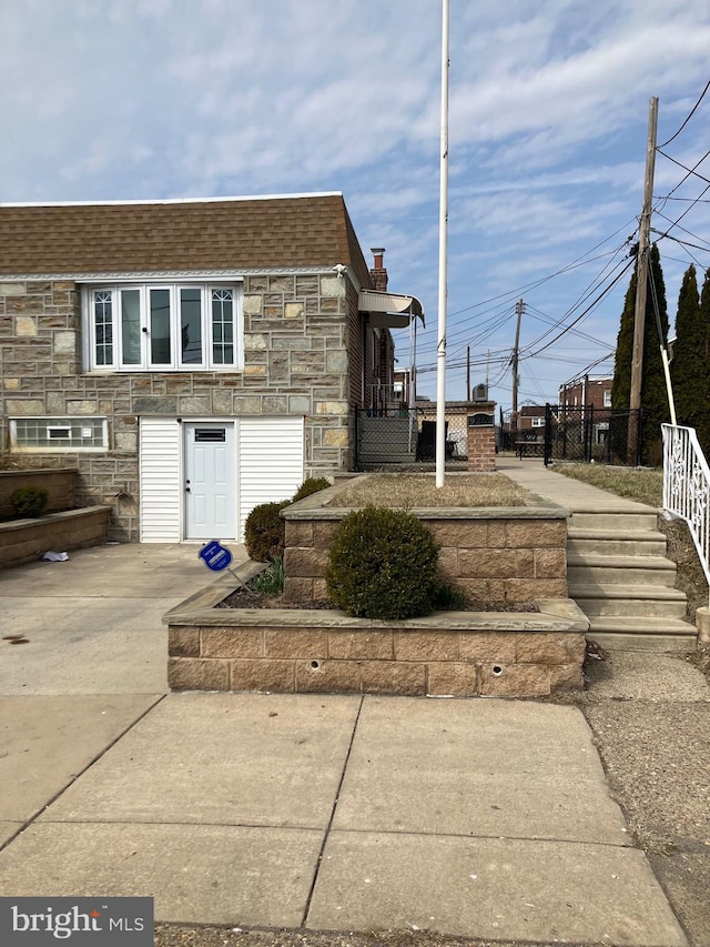 view of home's exterior featuring stone siding and roof with shingles