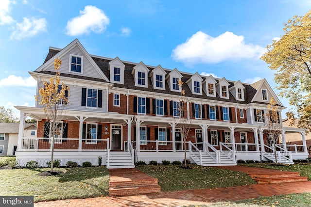 view of front of property featuring brick siding, a porch, and a front yard