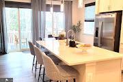 kitchen featuring a breakfast bar, light countertops, stainless steel refrigerator with ice dispenser, and a kitchen island with sink