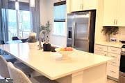 kitchen with a large island with sink, a kitchen breakfast bar, light countertops, and stainless steel fridge with ice dispenser