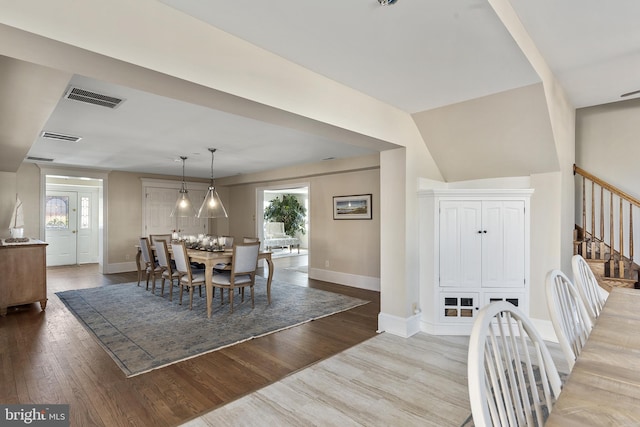 dining area with stairway, baseboards, visible vents, and light wood-type flooring