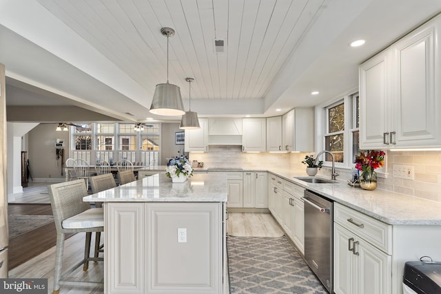 kitchen with a breakfast bar area, ceiling fan, a sink, white cabinets, and dishwasher