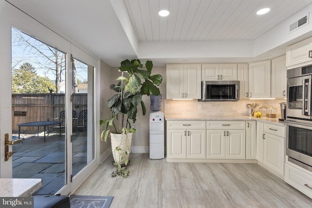 kitchen with a raised ceiling, visible vents, backsplash, and stainless steel appliances