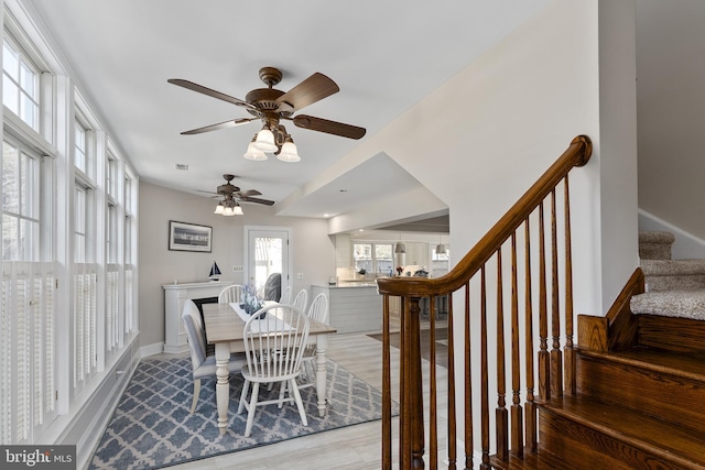 dining room featuring baseboards, stairs, ceiling fan, and wood finished floors