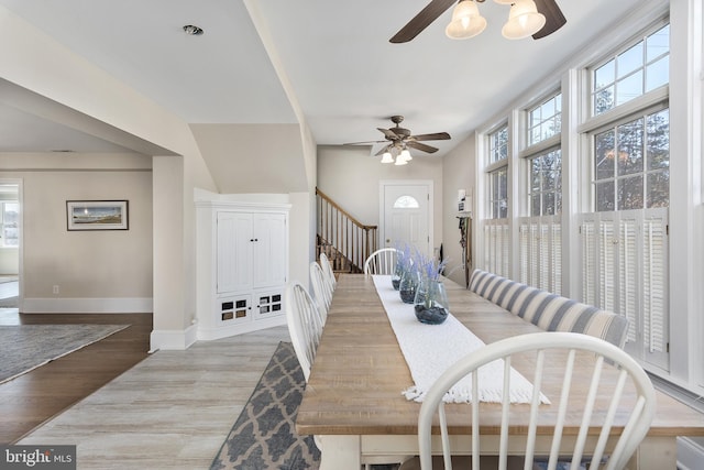 dining room with stairs, a ceiling fan, light wood-style floors, and baseboards