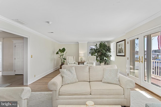 living room featuring plenty of natural light, crown molding, baseboards, and wood finished floors