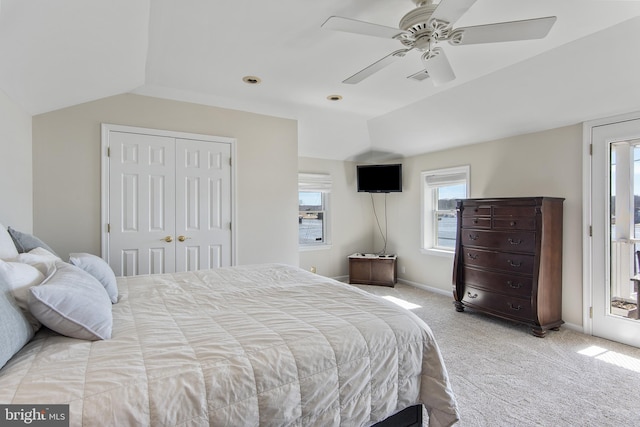 bedroom featuring light carpet, a ceiling fan, a closet, baseboards, and vaulted ceiling