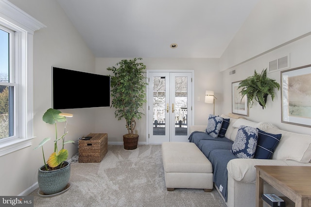 living room with a wealth of natural light, visible vents, lofted ceiling, and carpet