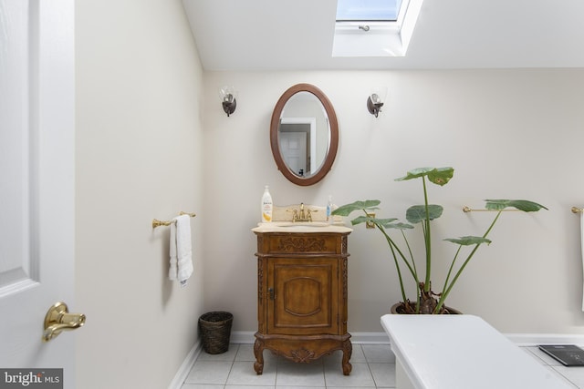 bathroom with tile patterned flooring, a skylight, vanity, and baseboards