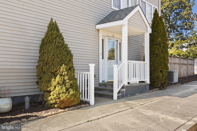 entrance to property featuring fence and roof with shingles