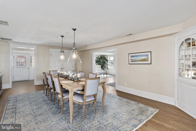 dining area with wood finished floors, visible vents, and baseboards