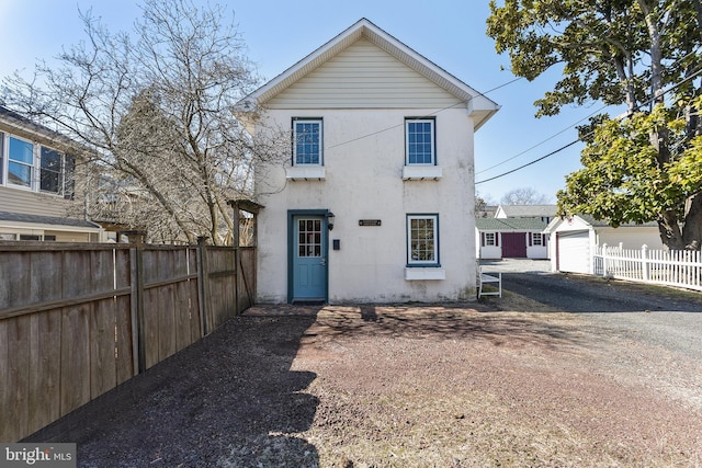 back of property with fence, a garage, and stucco siding