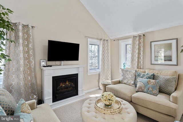 living room featuring baseboards, lofted ceiling, carpet, and a warm lit fireplace