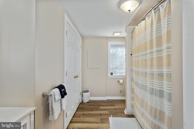 bathroom with a shower with shower curtain, baseboards, and wood finished floors