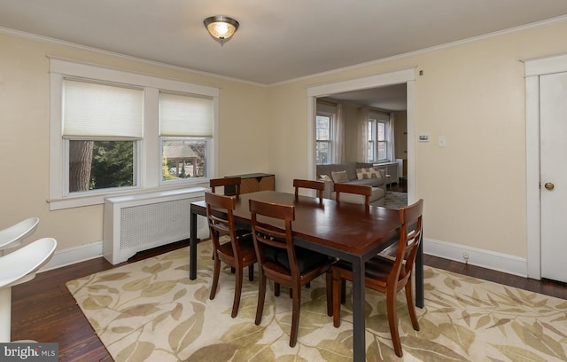 dining area featuring crown molding, baseboards, radiator heating unit, and light wood-style floors