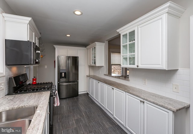 kitchen with decorative backsplash, dark wood-type flooring, glass insert cabinets, appliances with stainless steel finishes, and white cabinetry