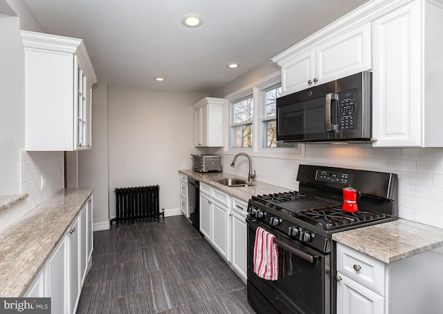 kitchen with white cabinets, radiator, black appliances, and a sink