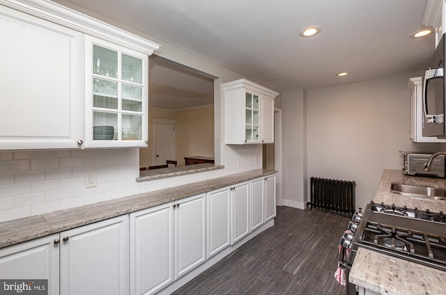 kitchen with radiator, recessed lighting, a sink, white cabinetry, and backsplash