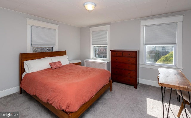 bedroom with a wall mounted AC, baseboards, and light carpet