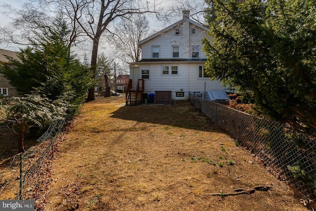 rear view of property with a chimney and fence