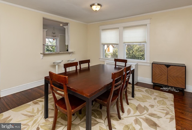 dining room with baseboards, wood finished floors, and crown molding