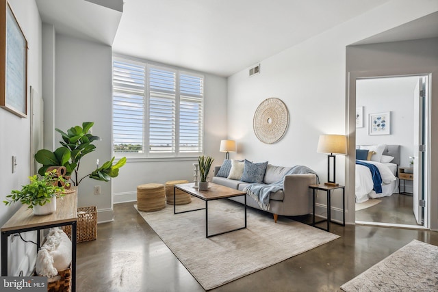 living area featuring visible vents, baseboards, and concrete flooring