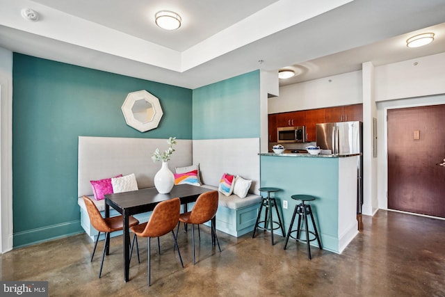 dining room with concrete flooring and baseboards