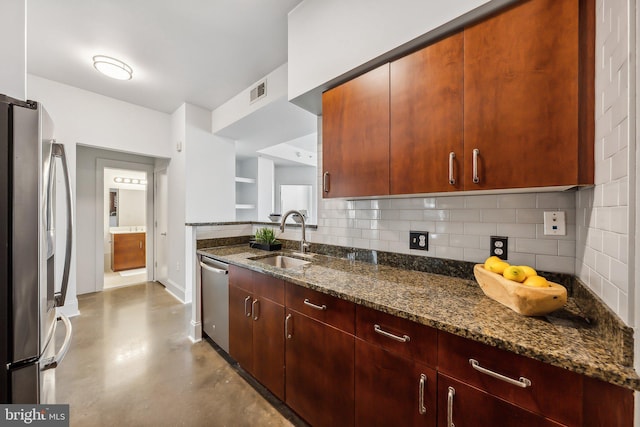 kitchen featuring dark stone counters, a sink, concrete flooring, appliances with stainless steel finishes, and tasteful backsplash