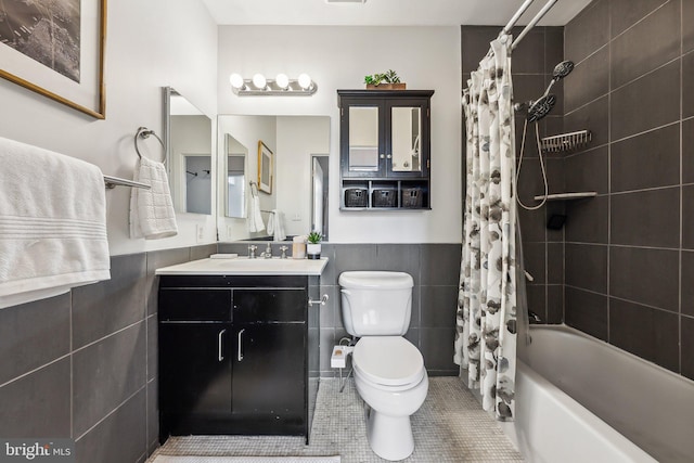 bathroom featuring a wainscoted wall, toilet, tile walls, tile patterned flooring, and vanity