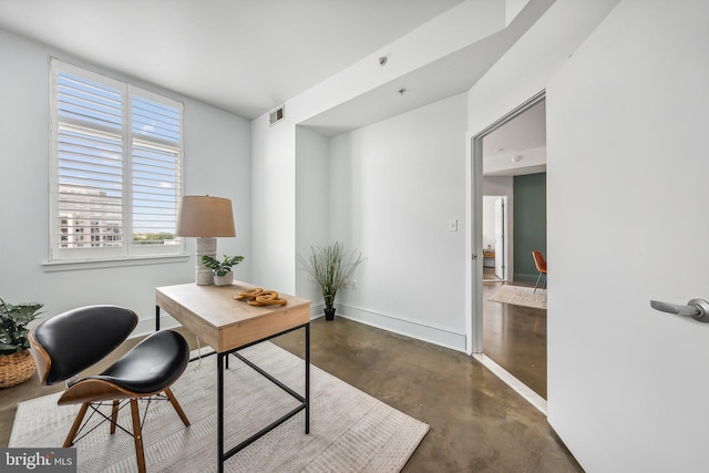 office with visible vents, baseboards, and finished concrete flooring