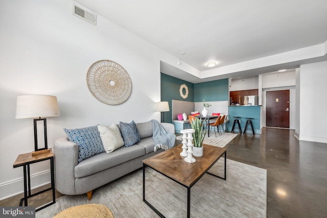 living area with visible vents, baseboards, and concrete floors