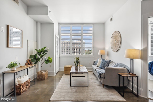 living area with visible vents, baseboards, and concrete floors