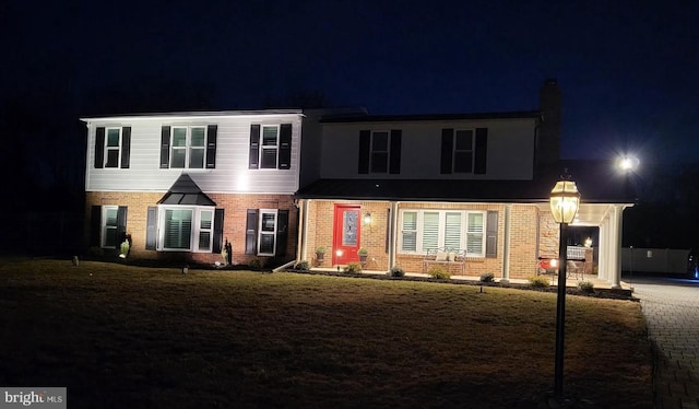 view of front of house with brick siding and a yard