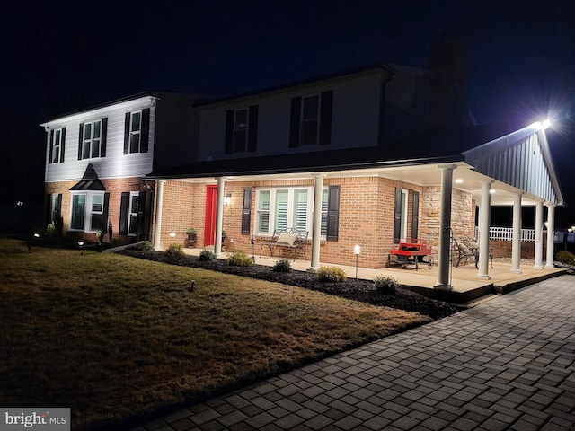 view of front of home featuring brick siding and a lawn