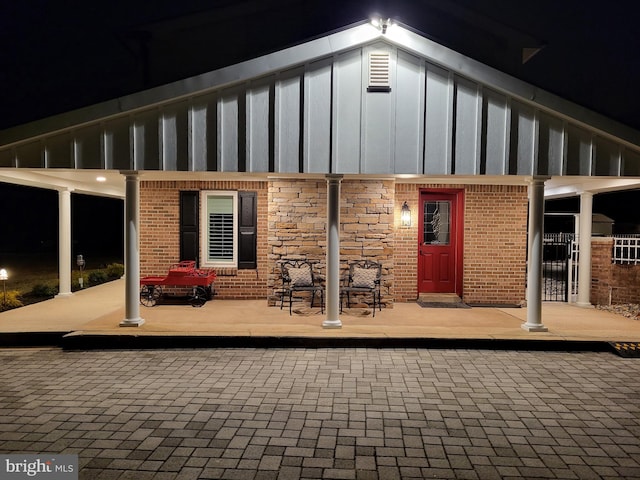 back of house featuring stone siding, brick siding, and board and batten siding