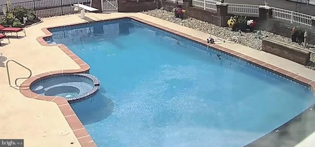 view of pool featuring a pool with connected hot tub, a patio, and fence