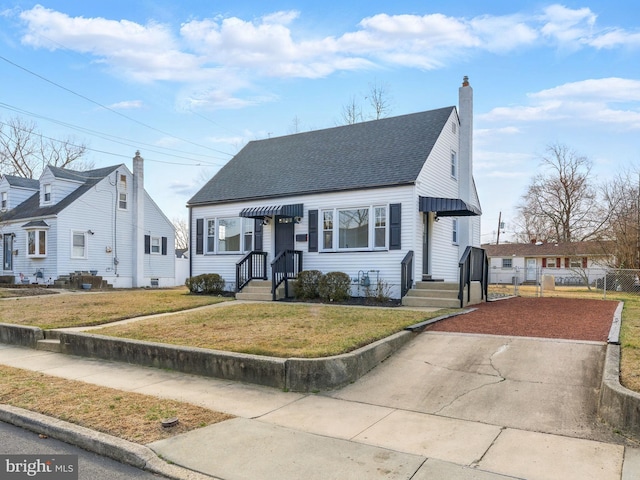 view of front of house with a front yard, fence, roof with shingles, and a chimney