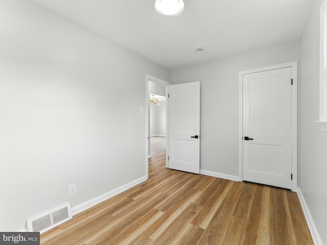 unfurnished bedroom featuring visible vents, baseboards, and wood finished floors