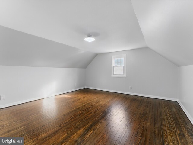 bonus room with vaulted ceiling, dark wood-style floors, and baseboards