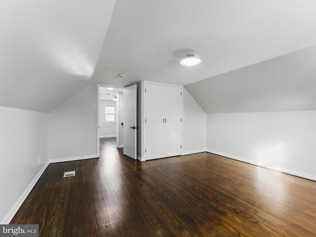 additional living space with hardwood / wood-style flooring, visible vents, baseboards, and vaulted ceiling