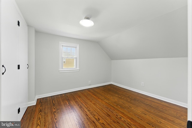 bonus room with vaulted ceiling, dark wood-style floors, and baseboards