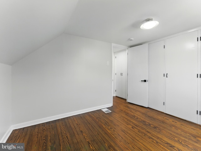 unfurnished bedroom featuring dark wood finished floors, lofted ceiling, visible vents, and baseboards