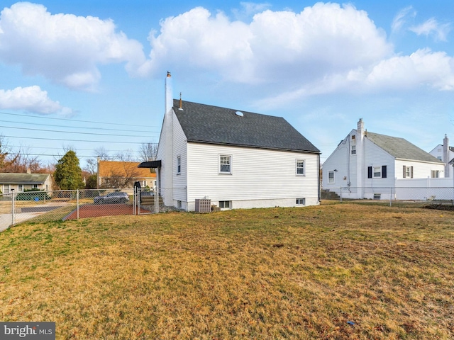 view of home's exterior with a gate, central AC unit, fence, roof with shingles, and a yard