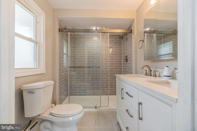 bathroom featuring double vanity, a sink, a shower stall, tile patterned floors, and toilet