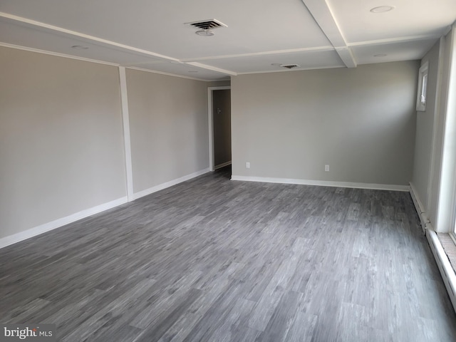 empty room with visible vents, baseboard heating, dark wood-type flooring, and baseboards