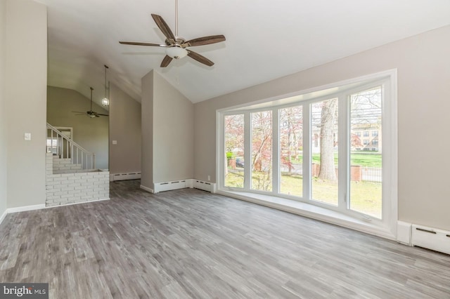 unfurnished living room featuring stairway, a baseboard heating unit, lofted ceiling, and wood finished floors