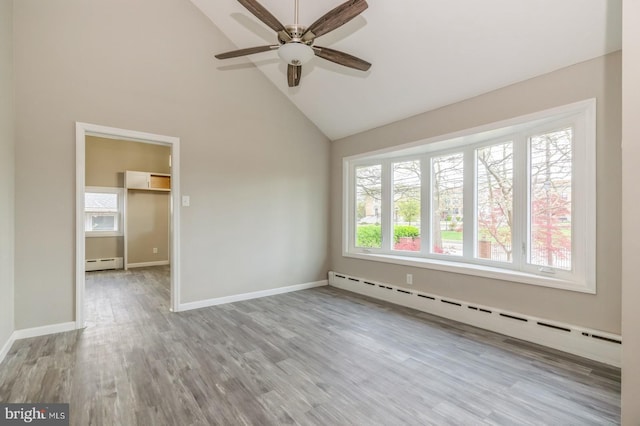 empty room with a baseboard heating unit, wood finished floors, and baseboards